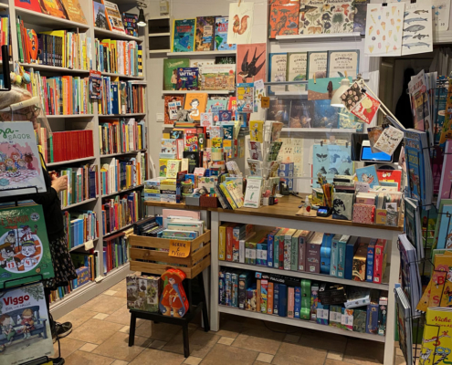 Interiör från bokhandel visar fullproppade bokhyllor och ställ med böcker