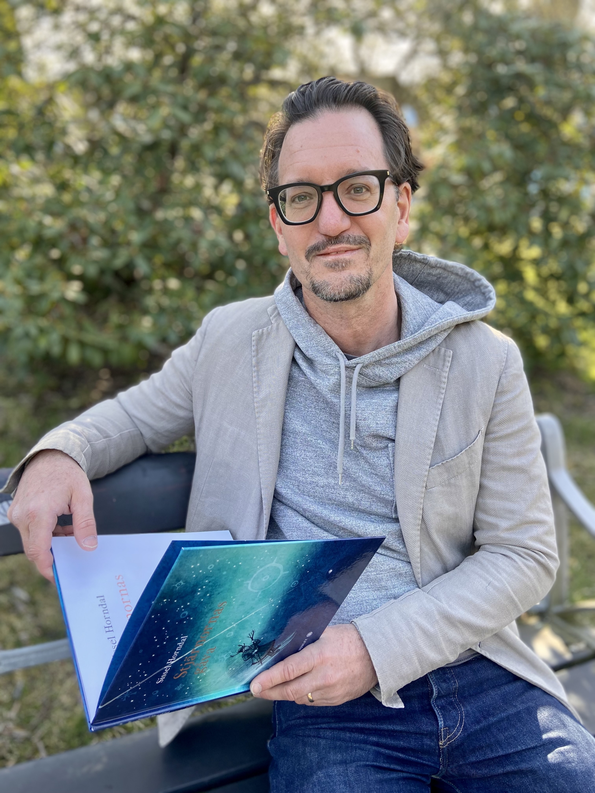 Olle Widhe sitter på bänk med samebok i hand