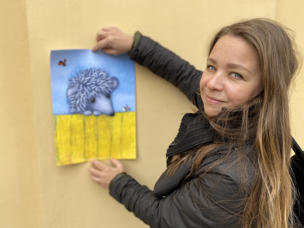Tania Goryushina håller upp affisch på omslagsbilden till Varför ingen klappar igelkotten.